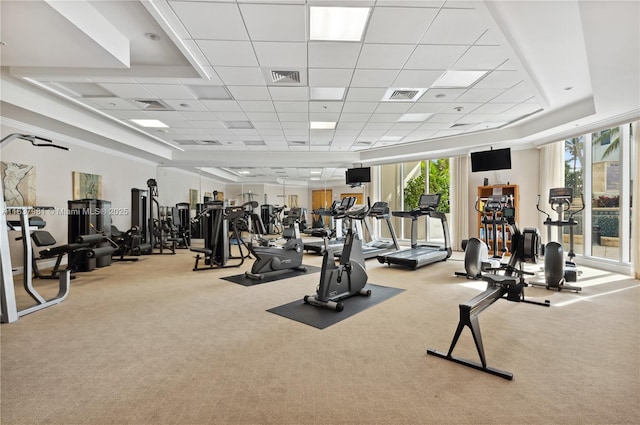 gym with a paneled ceiling and light carpet