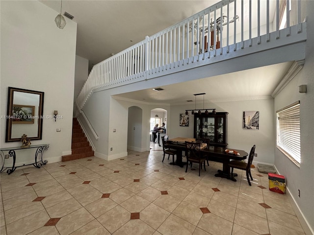 entryway with a towering ceiling, light tile patterned floors, and a healthy amount of sunlight