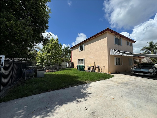 view of side of property featuring a carport and a lawn