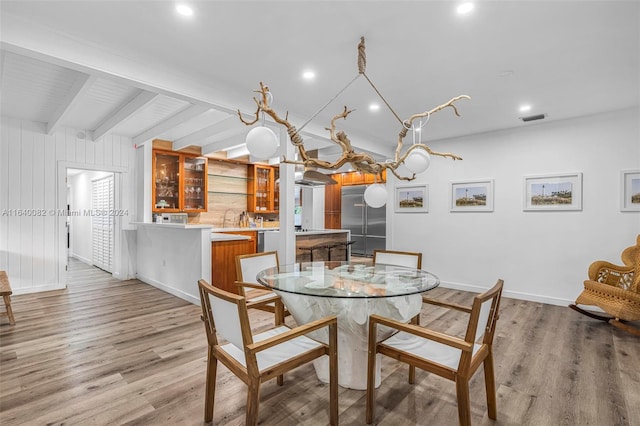 dining room with wood-type flooring, beam ceiling, and wooden walls