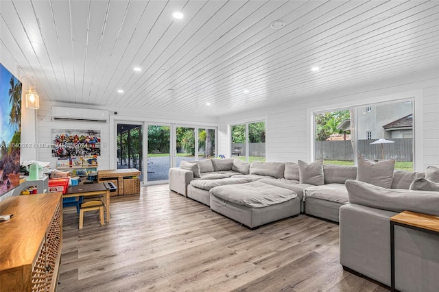 living room featuring wood walls, a wall unit AC, wood ceiling, and light hardwood / wood-style floors