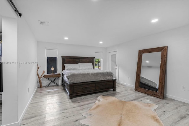 bedroom featuring light hardwood / wood-style floors and a barn door