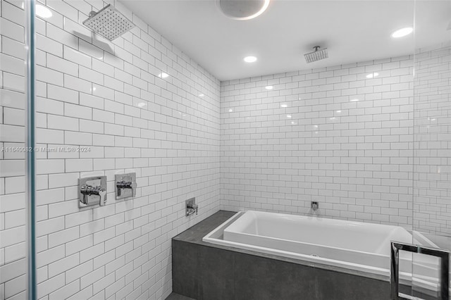 bathroom featuring plus walk in shower and tile walls