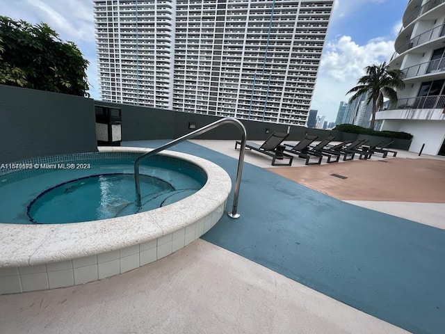 view of swimming pool with a view of city and a hot tub