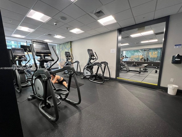 exercise room with baseboards, visible vents, and a drop ceiling