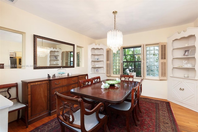 dining area with built in features, a chandelier, and hardwood / wood-style flooring