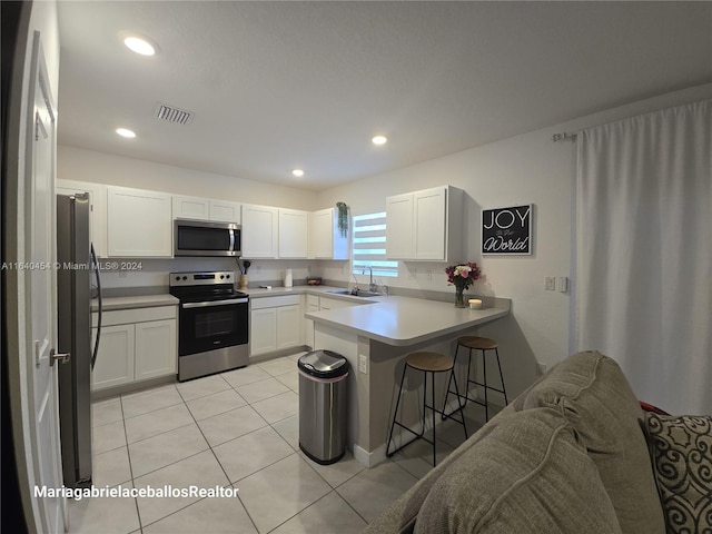 kitchen featuring kitchen peninsula, light tile patterned floors, stainless steel appliances, and a breakfast bar area