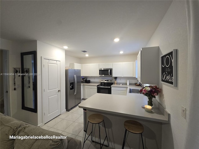 kitchen featuring kitchen peninsula, sink, light tile patterned floors, stainless steel appliances, and a breakfast bar area