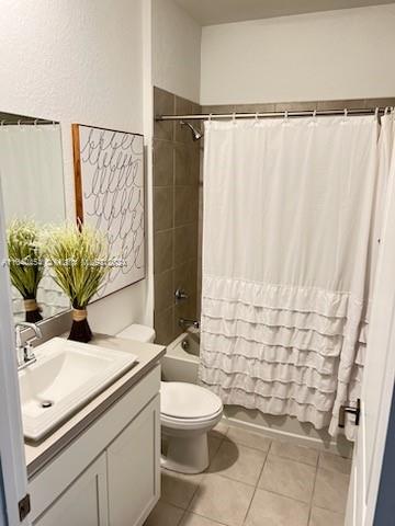 full bathroom with shower / bathtub combination with curtain, toilet, tile patterned floors, and vanity