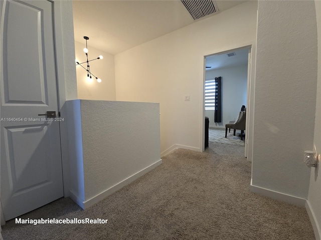 corridor featuring carpet flooring, lofted ceiling, and a chandelier