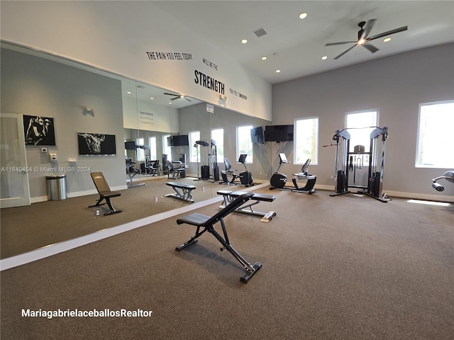 gym with ceiling fan, a high ceiling, carpet flooring, and plenty of natural light