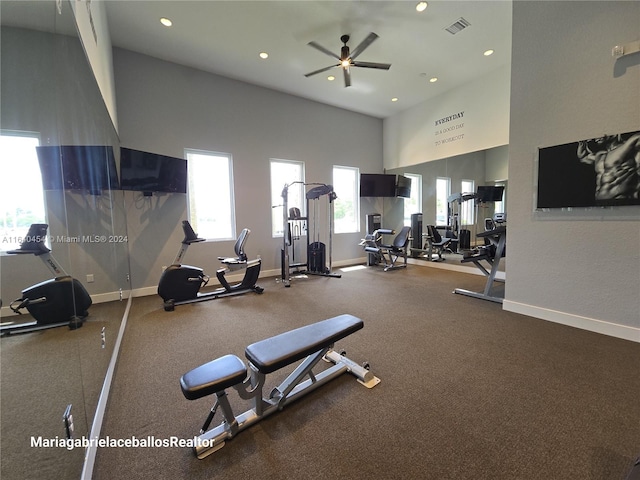 exercise room with ceiling fan and a towering ceiling