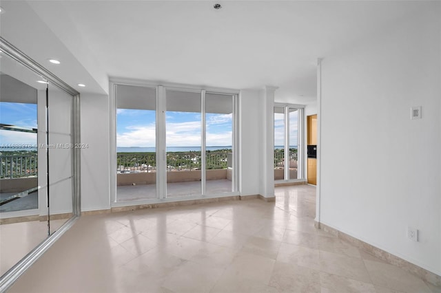 tiled spare room featuring a wall of windows