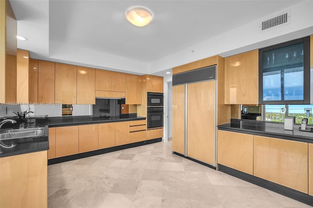 kitchen with black appliances, light brown cabinetry, dark stone countertops, and sink