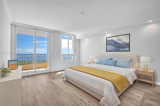 bedroom with light hardwood / wood-style flooring, a water view, access to exterior, and ornamental molding