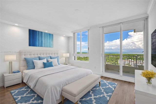 bedroom featuring wood-type flooring, ornamental molding, and access to exterior