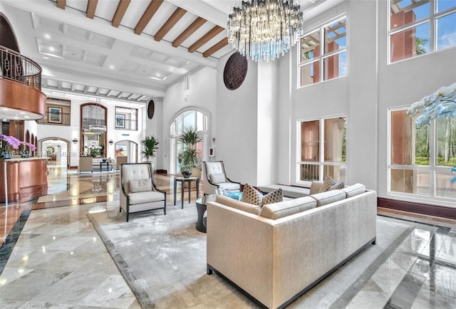 living room featuring beamed ceiling, a towering ceiling, a notable chandelier, and a wealth of natural light