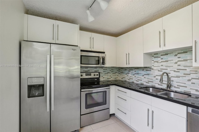 kitchen featuring decorative backsplash, a textured ceiling, appliances with stainless steel finishes, track lighting, and sink