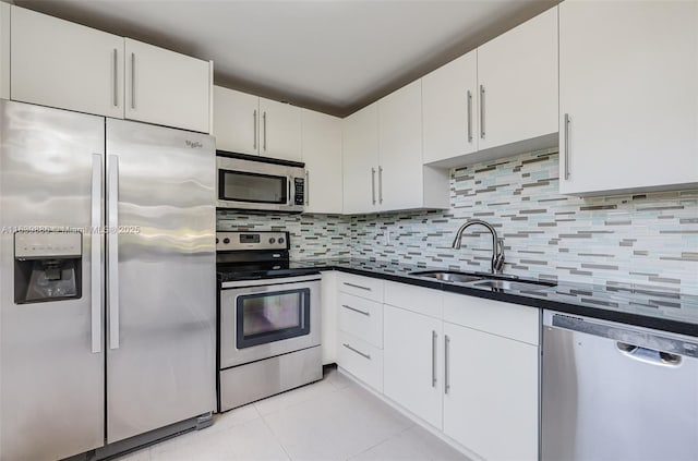 kitchen with white cabinetry, sink, decorative backsplash, light tile patterned floors, and stainless steel appliances