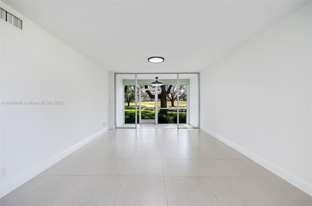 unfurnished room with light tile patterned floors and a wall of windows