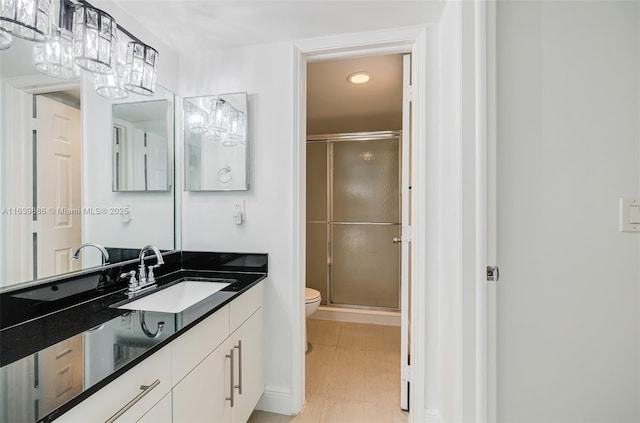 bathroom with vanity, a shower with door, and toilet