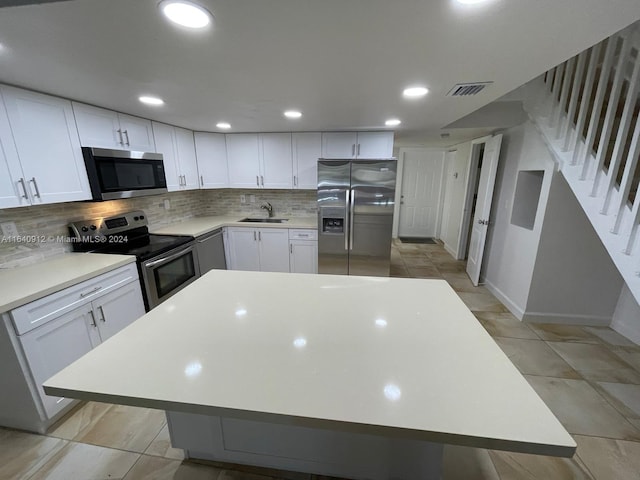 kitchen with decorative backsplash, stainless steel appliances, sink, and white cabinets