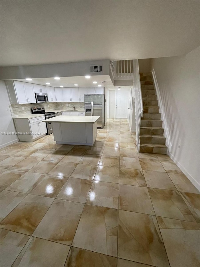 kitchen featuring stainless steel appliances, white cabinetry, a center island, and light tile patterned floors