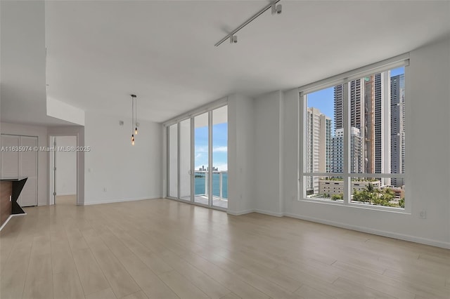 601 NE 27th St Unit 1206, Miami, FL 33137 - unfurnished living room with light wood-type flooring, baseboards, and a water view