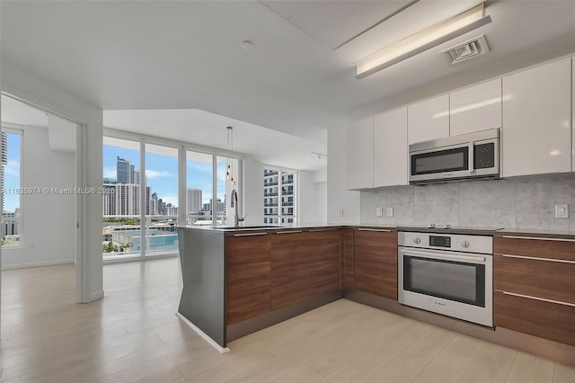 601 NE 27th St Unit 1206, Miami, FL 33137 - kitchen with stainless steel appliances, modern cabinets, a peninsula, white cabinets, and backsplash