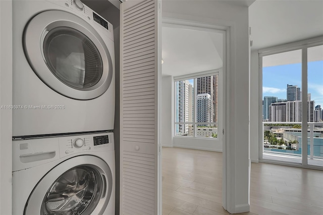 601 NE 27th St Unit 1206, Miami, FL 33137 - laundry room with stacked washer and clothes dryer, a view of city, light wood finished floors, and baseboards