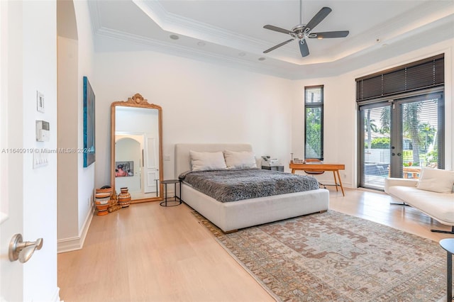 bedroom with access to outside, light hardwood / wood-style flooring, ceiling fan, and a raised ceiling