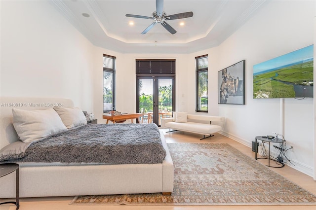 bedroom featuring ceiling fan, crown molding, light wood-type flooring, and a tray ceiling