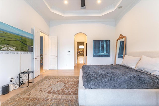 bedroom with crown molding, light wood-type flooring, and a raised ceiling