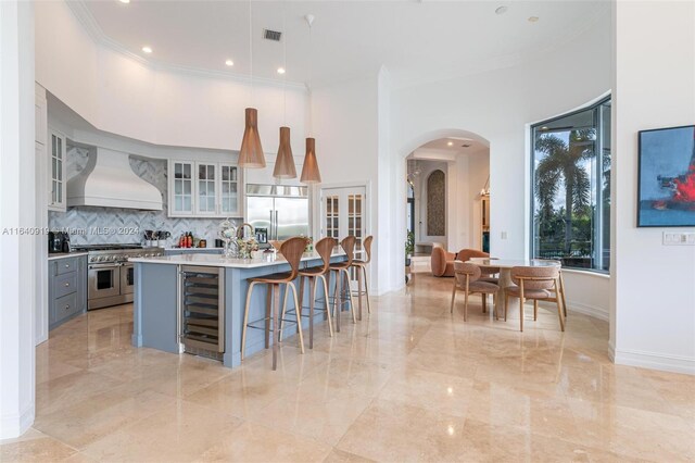 kitchen featuring wine cooler, gray cabinets, hanging light fixtures, high quality appliances, and custom range hood