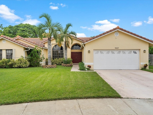 mediterranean / spanish home with a front yard and a garage