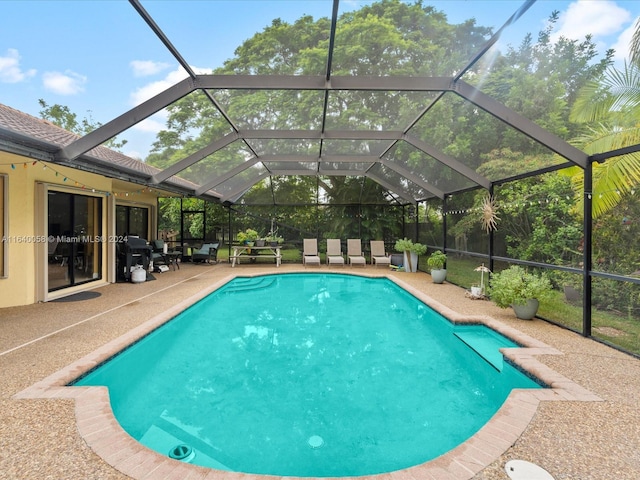 view of swimming pool featuring glass enclosure and a patio