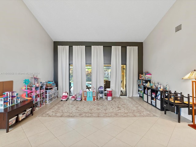 rec room featuring lofted ceiling, light tile patterned flooring, and a textured ceiling