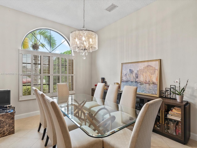 dining room with a textured ceiling, plenty of natural light, an inviting chandelier, and light tile patterned floors