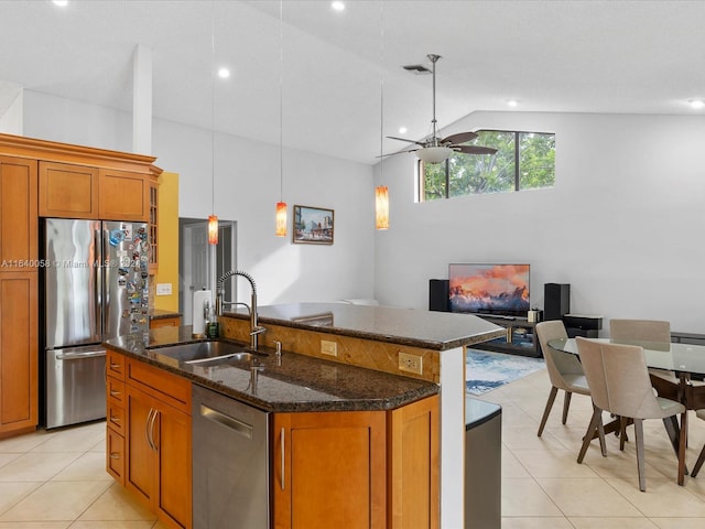 kitchen with dark stone countertops, sink, ceiling fan, appliances with stainless steel finishes, and a center island with sink