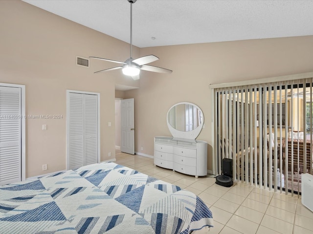 bedroom featuring ceiling fan, high vaulted ceiling, two closets, and light tile patterned flooring