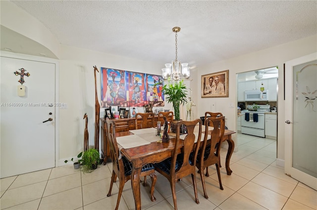 tiled dining space with a notable chandelier and a textured ceiling