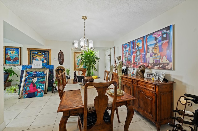 dining room featuring a textured ceiling, a notable chandelier, and light tile patterned floors