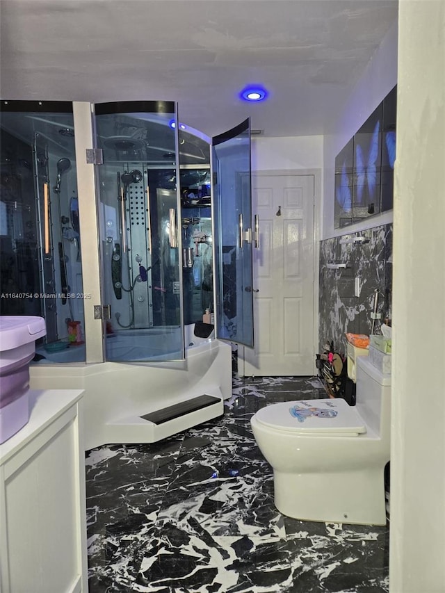 bathroom featuring a shower with door, vanity, and toilet