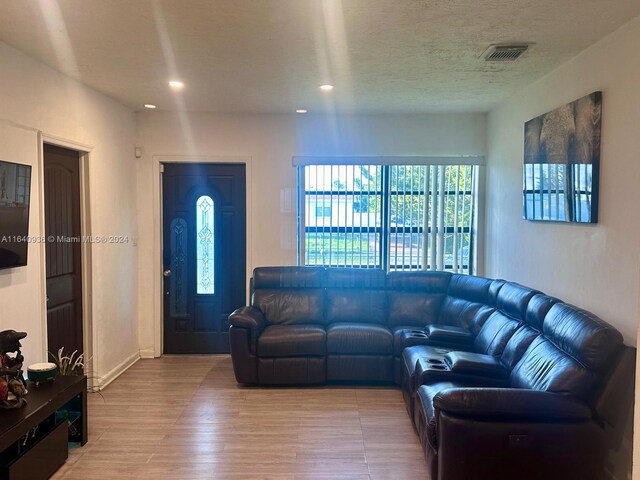 living room featuring light hardwood / wood-style flooring and a textured ceiling