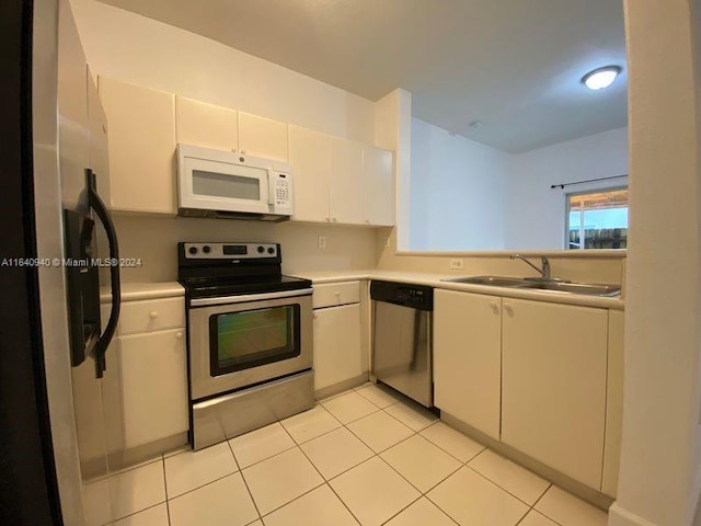 kitchen featuring light tile patterned flooring, sink, stainless steel appliances, and white cabinetry