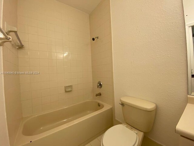 bathroom with toilet, tile patterned floors, and tiled shower / bath