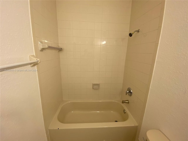 bathroom featuring tiled shower / bath and toilet