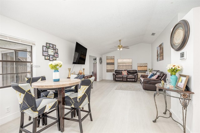 dining space with vaulted ceiling, light hardwood / wood-style flooring, a textured ceiling, and ceiling fan