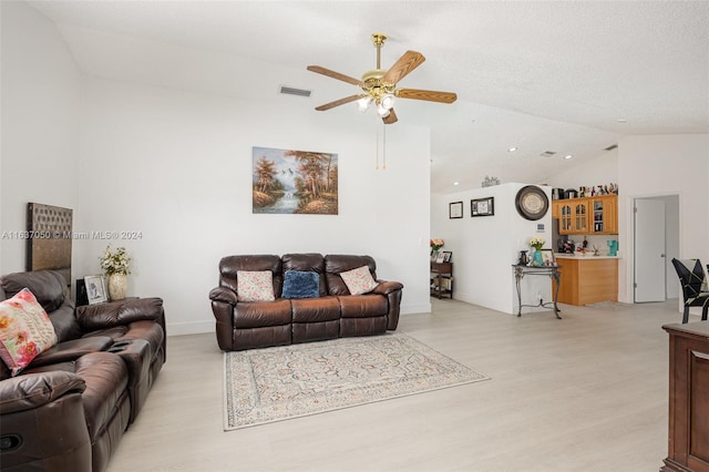 living room with lofted ceiling, a textured ceiling, light wood-type flooring, and ceiling fan