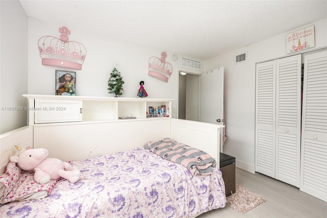 bedroom featuring a closet, wood-type flooring, and a textured ceiling